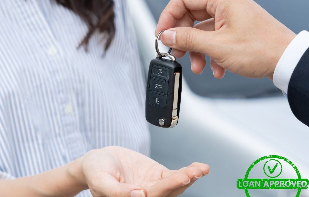 A person handing over car keys to another person, symbolizing auto loan approval and vehicle ownership transfer.