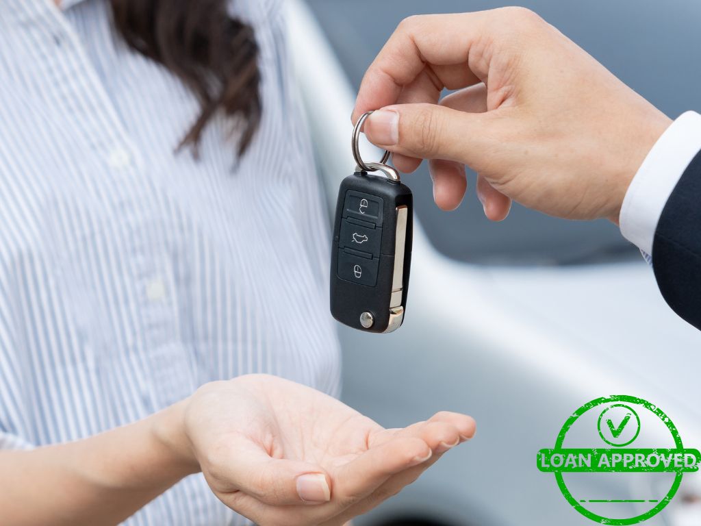 A person handing over car keys to another person, symbolizing auto loan approval and vehicle ownership transfer.