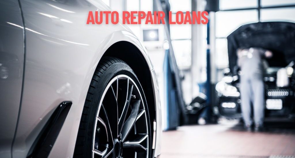 Close-up of a car wheel rim in an auto repair shop, with a blurred mechanic working under a vehicle and overlay text “AUTO REPAIR LOANS.”